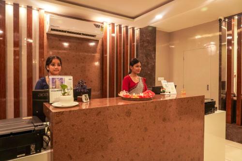 two women sitting at a counter in an office at Hotel Ratneswar in Alīpur Duār