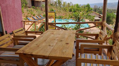 a wooden table and chairs on a patio with a pool at Akagera Park Inn in Akagera