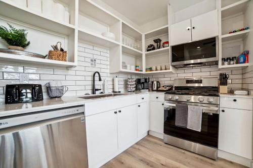 Una cocina con gabinetes blancos y electrodomésticos de acero inoxidable. en Elegant Modern A-Frame Surrounded by Nature in Texas, en Fourth Crossing