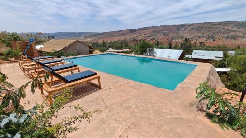 a swimming pool with two lounge chairs next to it at Akagera Park Inn in Akagera