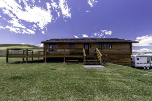 a log cabin in a field with a trailer at Secluded Cabin Rental for a Peaceful Vacation in Montana in Pony