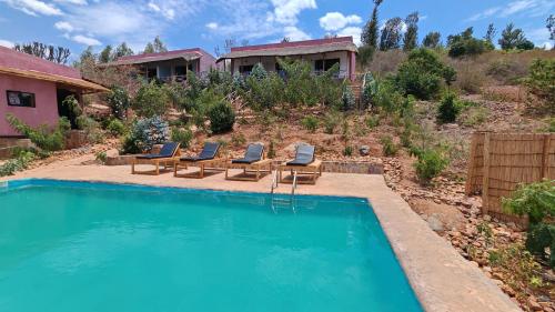 a swimming pool with lounge chairs and a house at Akagera Park Inn in Akagera