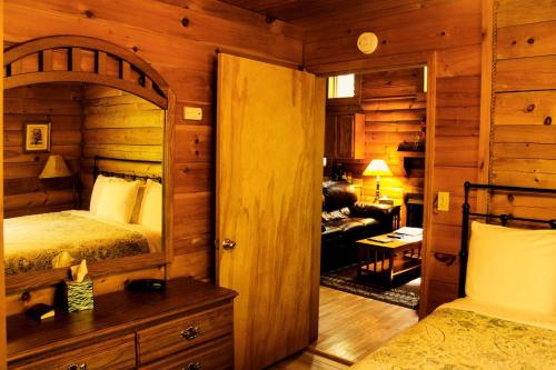 a bedroom with a bed and a living room at Charming Cabin Rental in the Forest near Beckley, West Virginia in Hico