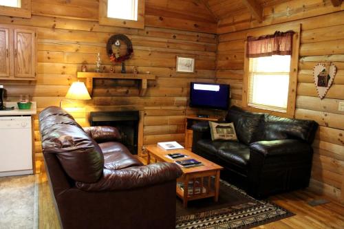 a living room with leather furniture in a log cabin at Charming Cabin Rental in the Forest near Beckley, West Virginia in Hico