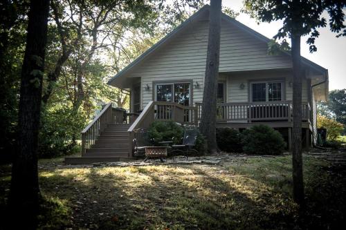 a small white house with a porch and stairs at Wonderful Lakefront Cabin with Hot-tub in Carbondale, Illinois in Etherton