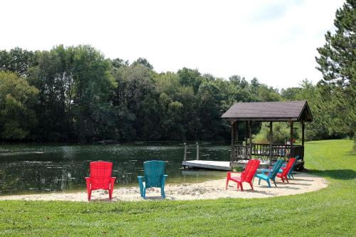 a group of colorful chairs sitting on a beach next to a boat at Rustic Family Cabin Rental with a Fire Pit near Wisconsin Dells in Tomah