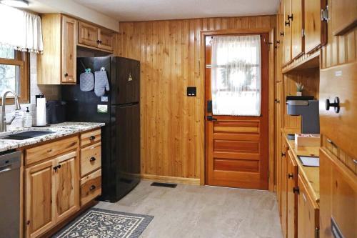 a kitchen with wooden cabinets and a black refrigerator at Cozy Mountain Cabin with Hot Tub & Scenic Views in Stanley, Virginia in Marksville