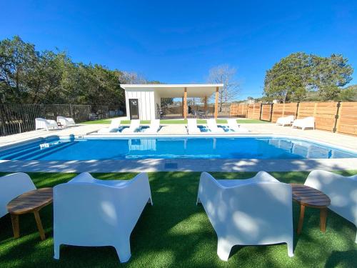a swimming pool with white chairs and a swimming poolvisor at Beautiful Tented Cabin in Texas for Glamping by Guadalupe River in Hunt
