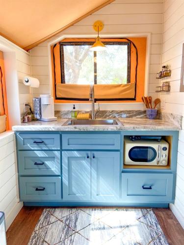 a blue kitchen with a sink and a microwave at Beautiful Tented Cabin in Texas for Glamping by Guadalupe River in Hunt