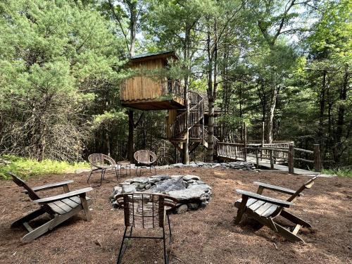 a group of chairs and a tree house in the woods at Eco-Friendly, Abstract Treehouse Surrounded by Wildlife and Hiking Trails For a Special Getaway in Sparrow Bush, New York in Cahoonzie