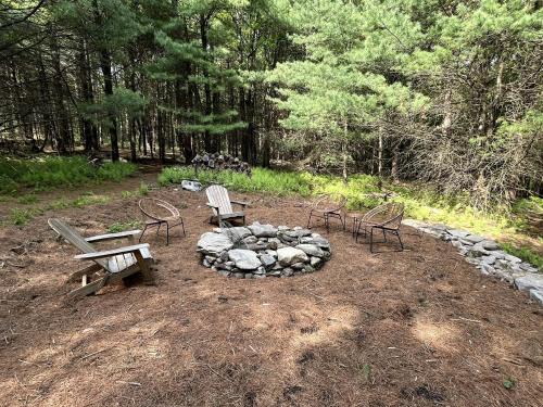 a group of chairs sitting around a fire pit at Eco-Friendly, Abstract Treehouse Surrounded by Wildlife and Hiking Trails For a Special Getaway in Sparrow Bush, New York in Cahoonzie