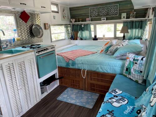 a bedroom with a bed and a kitchen with a stove at Marble Falls Retro Caravan Glamping: Your Vintage Getaway Awaits in Marble Falls