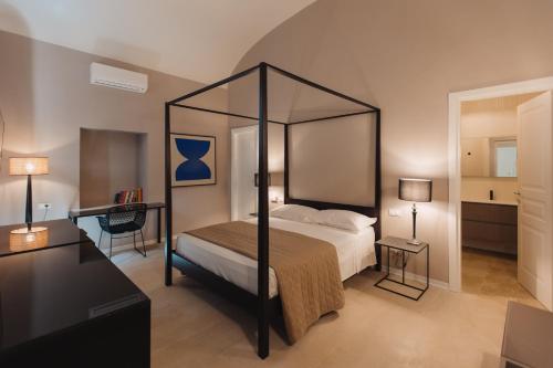a bedroom with a canopy bed and a desk at Dimora Crocefisso in Noto