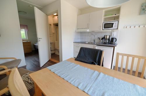 a kitchen and dining room with a table and a microwave at Apelvikstrand Lägenheter in Varberg