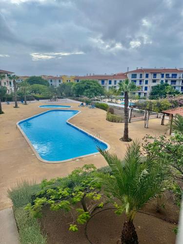 ein Schwimmbad in einem Ferienresort mit Palmen und Gebäuden in der Unterkunft Studio with pool in Santa Maria