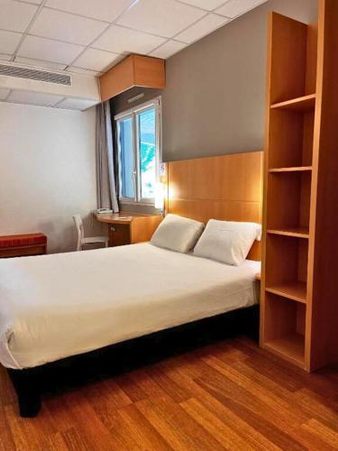 Ibis Vitré Centre في فيتري: غرفة نوم بها سرير ورف كتب