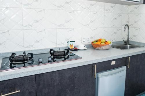 a kitchen counter with a stove and a sink at Mica Apartments in Sere Kunda