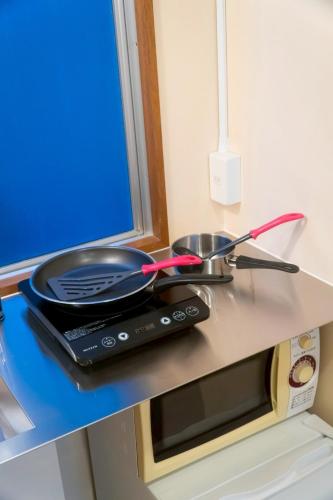 a frying pan on top of a microwave at Tokyo Tower Cozy Stay 201 Tamachi & Mita Access in Wada