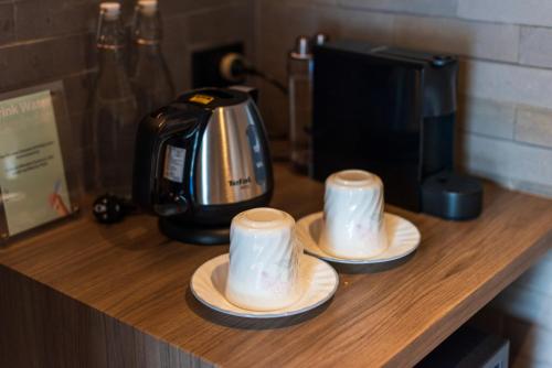 two cups on a counter next to a coffee maker at Na Tanao 1969 in Bangkok