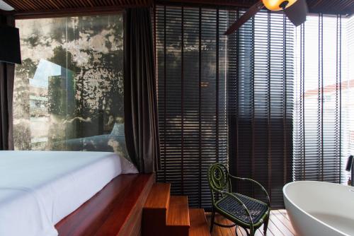a bedroom with a bed and a tub and a sink at Na Tanao 1969 in Bangkok