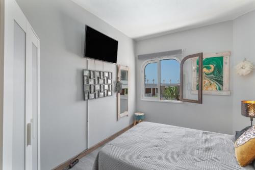 una camera da letto con un letto e una TV a parete di Puerto Rico a 2 minutos de la playa a Mogán