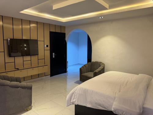 a bedroom with a bed and two chairs and a tv at D5 future homes hotel & apartment in Benin City