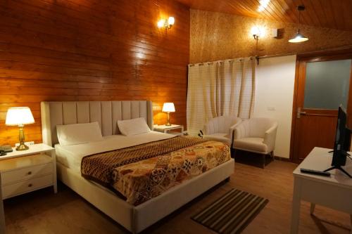 a bedroom with a bed and a desk and a chair at Conifer Resort in Jajal