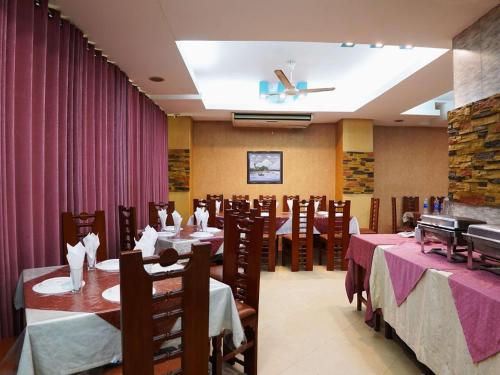 a restaurant with tables and chairs and a ceiling at Britannia Hotel in Sylhet