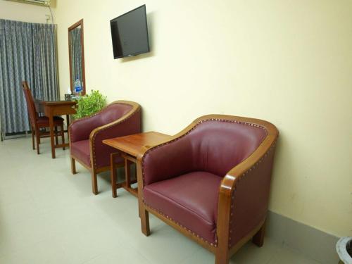 a waiting room with two chairs and a table and a tv at Britannia Hotel in Sylhet