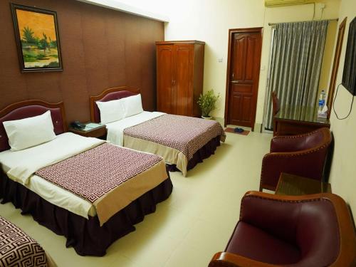 a hotel room with two beds and a chair at Britannia Hotel in Sylhet