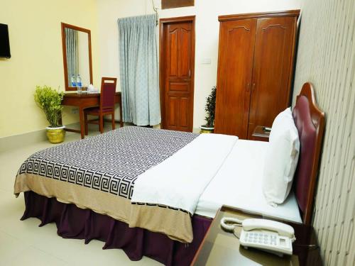a hotel room with a bed and a phone on a desk at Britannia Hotel in Sylhet