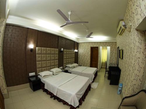 a bedroom with two beds and a ceiling fan at Britannia Hotel in Sylhet