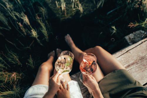 a person sitting on a bench holding wine glasses at Alpzitt-Chalets in Burgberg