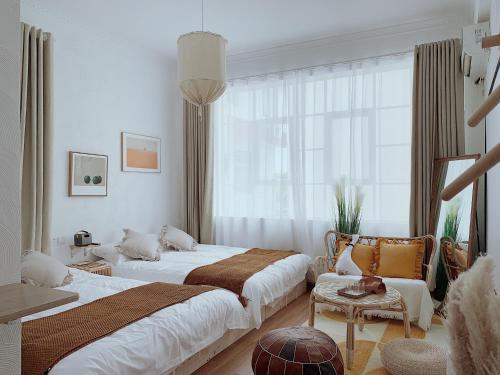 Un dormitorio con dos camas y una silla y una ventana. en Sinanli Flower House Courtyard, en Jiazaiwei