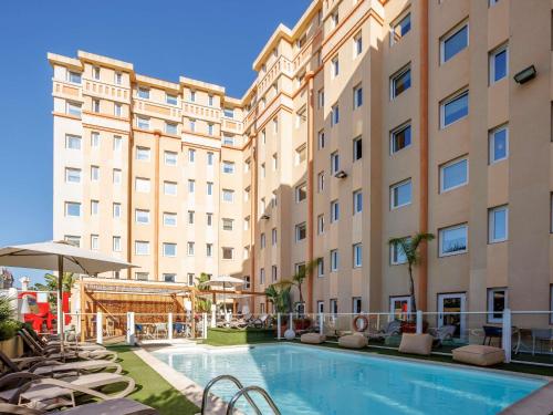 a hotel with a swimming pool in front of a building at ibis Nice Centre Gare in Nice