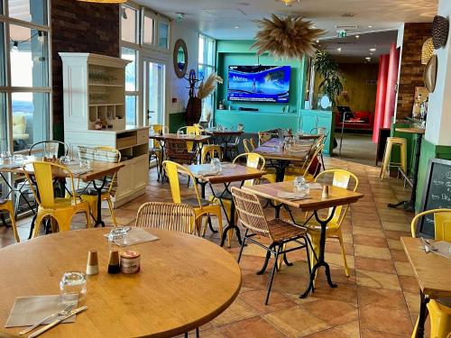 a restaurant with wooden tables and chairs and a tv at ibis Montpellier Centre Polygone in Montpellier