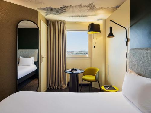 a hotel room with a bed and a chair and a window at ibis Nice Centre Gare in Nice