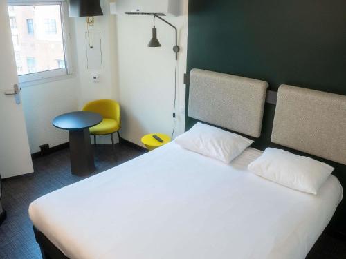 a bedroom with a white bed and a yellow chair at ibis Nice Centre Gare in Nice