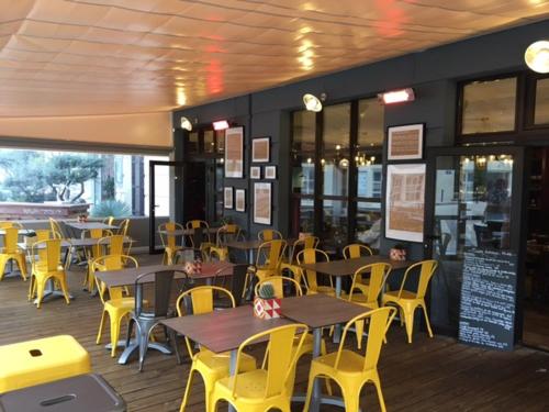 a restaurant with wooden tables and yellow chairs at ibis Montpellier Centre Polygone in Montpellier