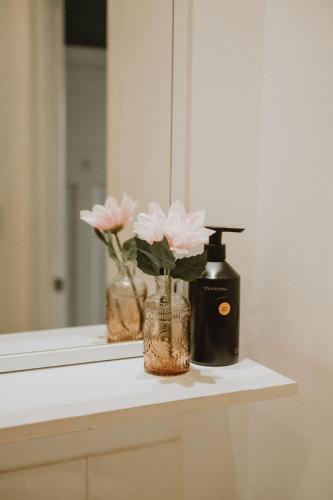 a bathroom counter with a bottle of soap and flowers at The Kentish Tasmania in Oatlands