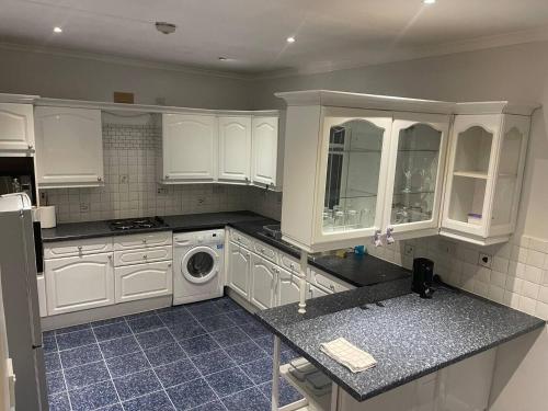 Una cocina con gabinetes blancos y lavadora. en Hendon Home, en Hendon