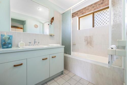 a white bathroom with a sink and a shower at Sandy Surfer - Tweed Coast Holidays in Cabarita Beach
