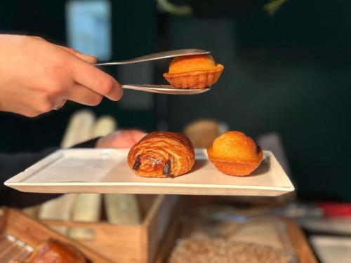 a person is holding a plate with food on a spoon at Ibis Pau Centre in Pau
