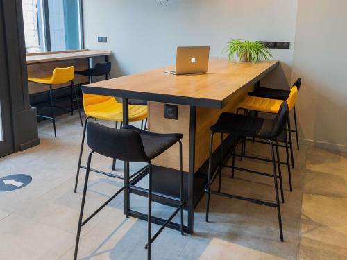 a bar with yellow chairs and a laptop on a table at Ibis Pau Centre in Pau