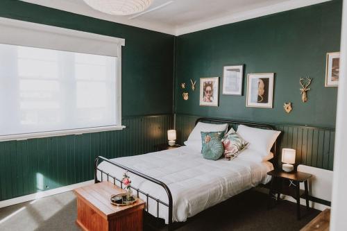 a bedroom with green walls and a bed with pillows at The Kentish Tasmania in Oatlands