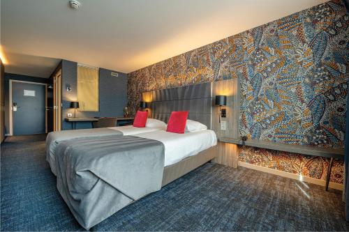 a hotel room with a large bed with red pillows at Van der Valk Hotel Liège Congres in Liège