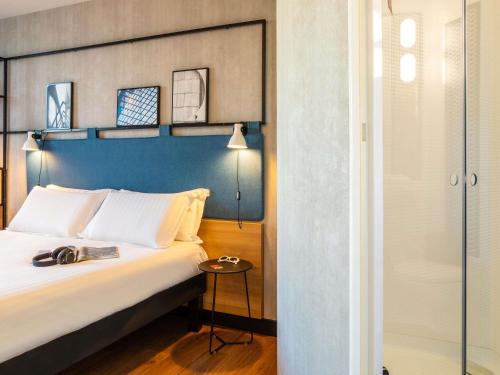a bedroom with a large bed with a blue headboard at ibis Paris CDG Airport in Roissy-en-France