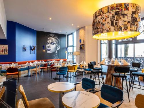 a restaurant with tables and chairs and a large chandelier at ibis Paris La Villette Cité des Sciences 19ème in Paris