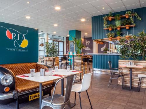 a restaurant with tables and chairs and plants at ibis Paris CDG Airport in Roissy-en-France
