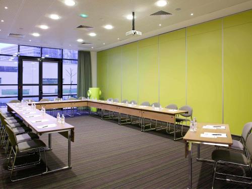 a conference room with tables and chairs and green walls at ibis Paris CDG Airport in Roissy-en-France